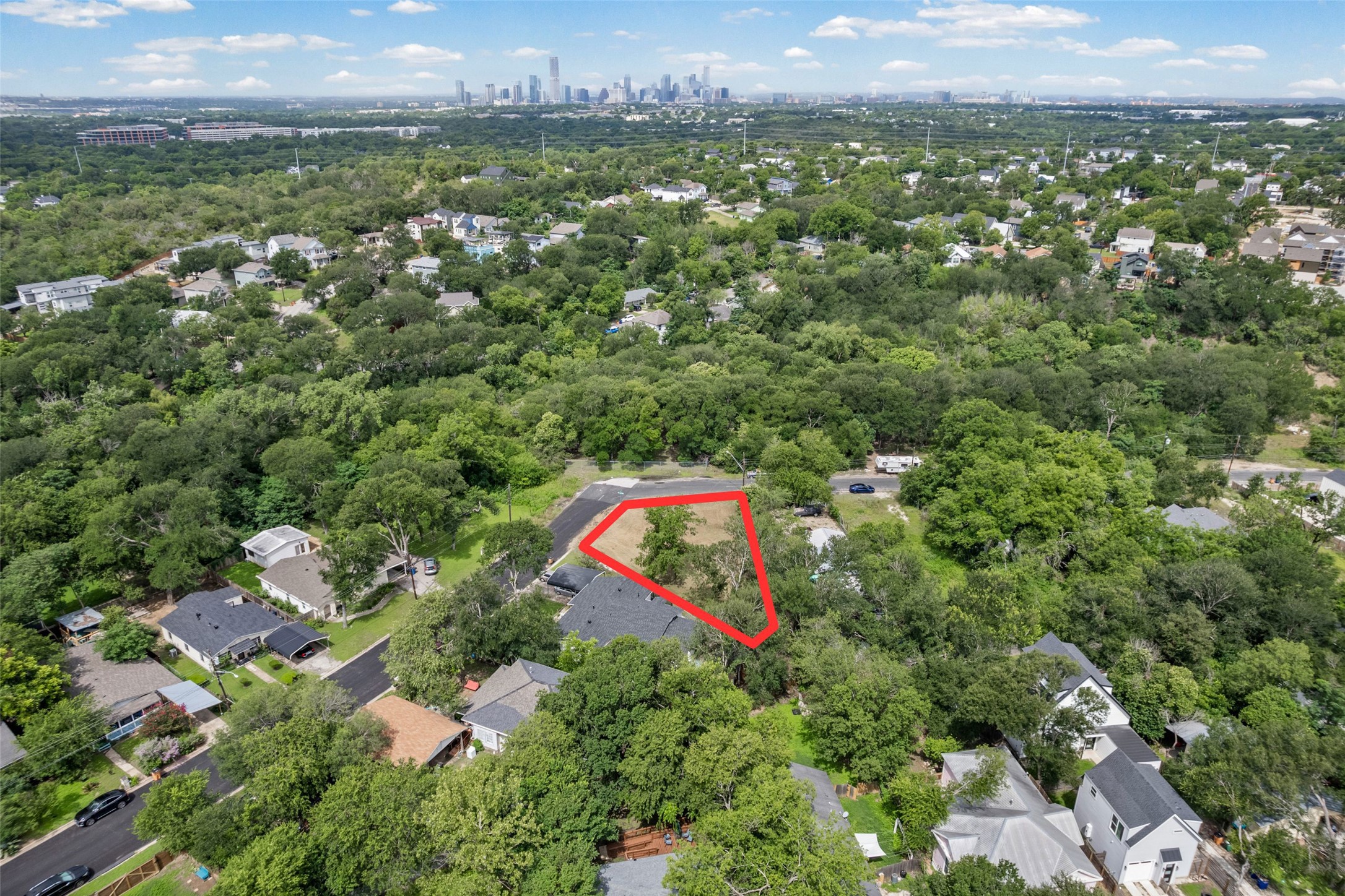 1201 Fort Branch Boulevard Austin, TX 78721 - Photo 2 of 19 A valuable lot awaits with abundant tree coverage, set against a distant cityscape backdrop.