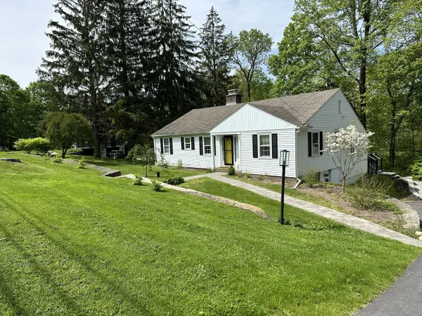 a white house with a small yard and large trees