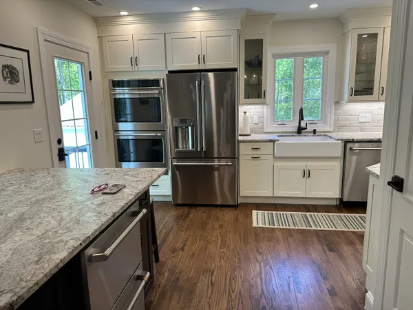 a kitchen with granite countertop a refrigerator oven a sink and wooden floors