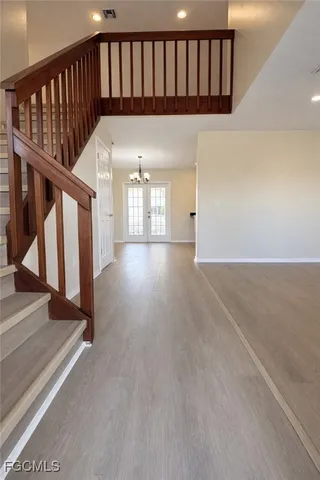 an empty room with chandelier fan and windows