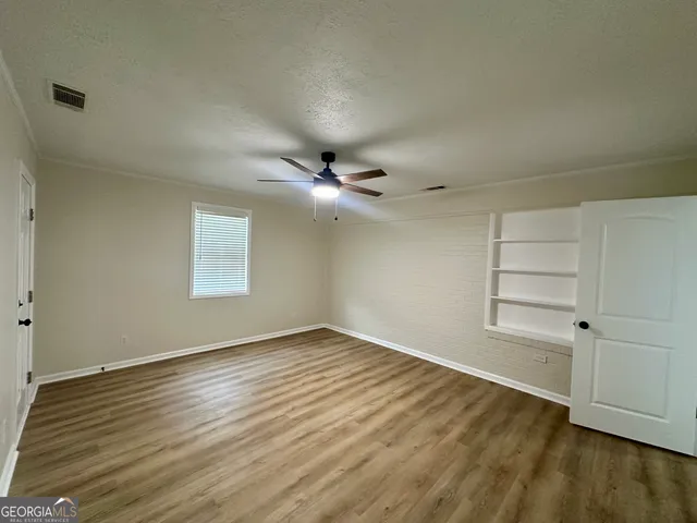 an empty room with wooden floor closet and windows
