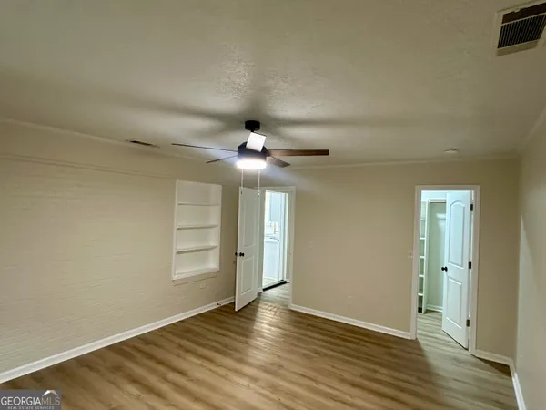 an empty room with wooden floor chandelier fan and windows