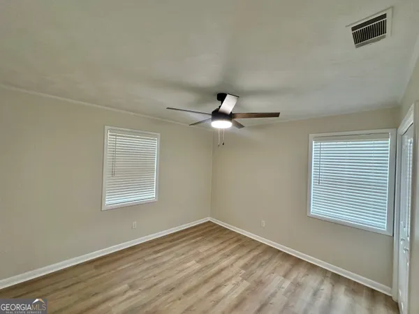 a view of empty room with wooden floor and fan
