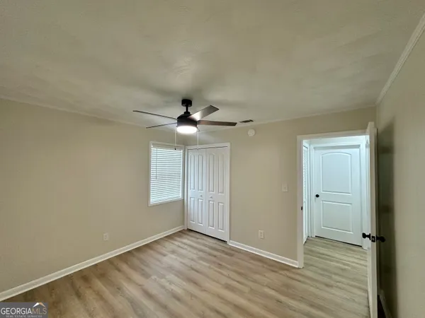 an empty room with wooden floor a ceiling fan and windows