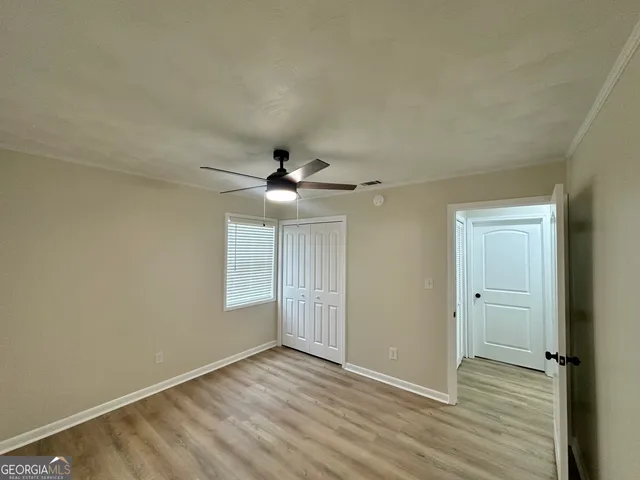 an empty room with wooden floor a ceiling fan and windows