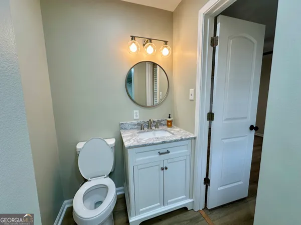 a bathroom with a toilet sink vanity and mirror