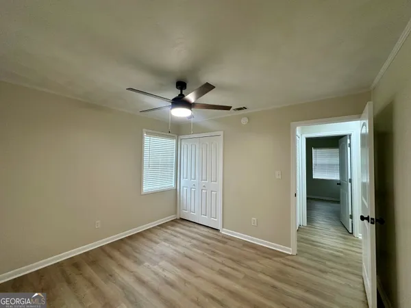 an empty room with wooden floor a ceiling fan and windows
