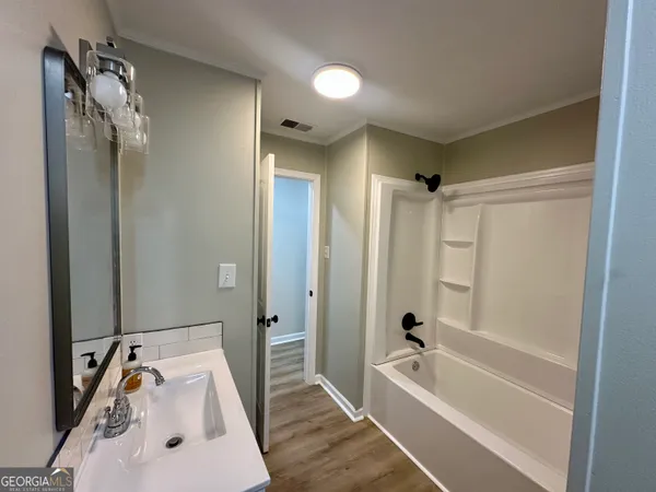 a bathroom with a tub sink vanity and mirror