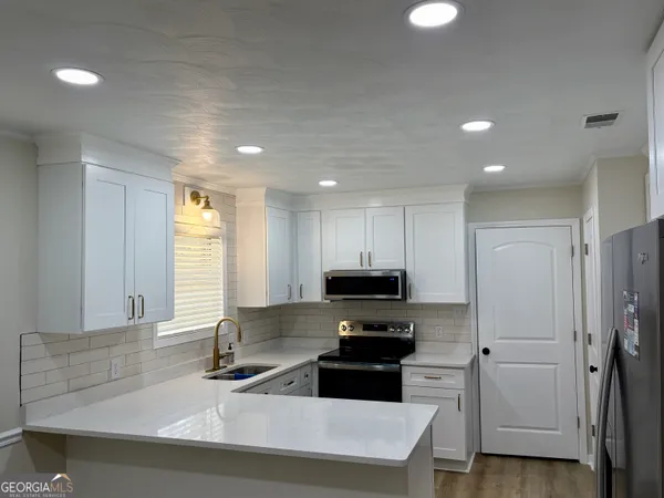 a kitchen with stainless steel appliances a sink a stove a microwave a refrigerator and cabinets