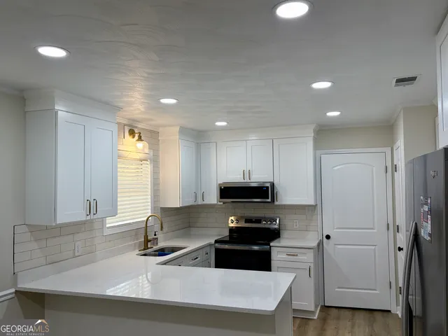 a kitchen with stainless steel appliances a sink a stove a microwave a refrigerator and cabinets