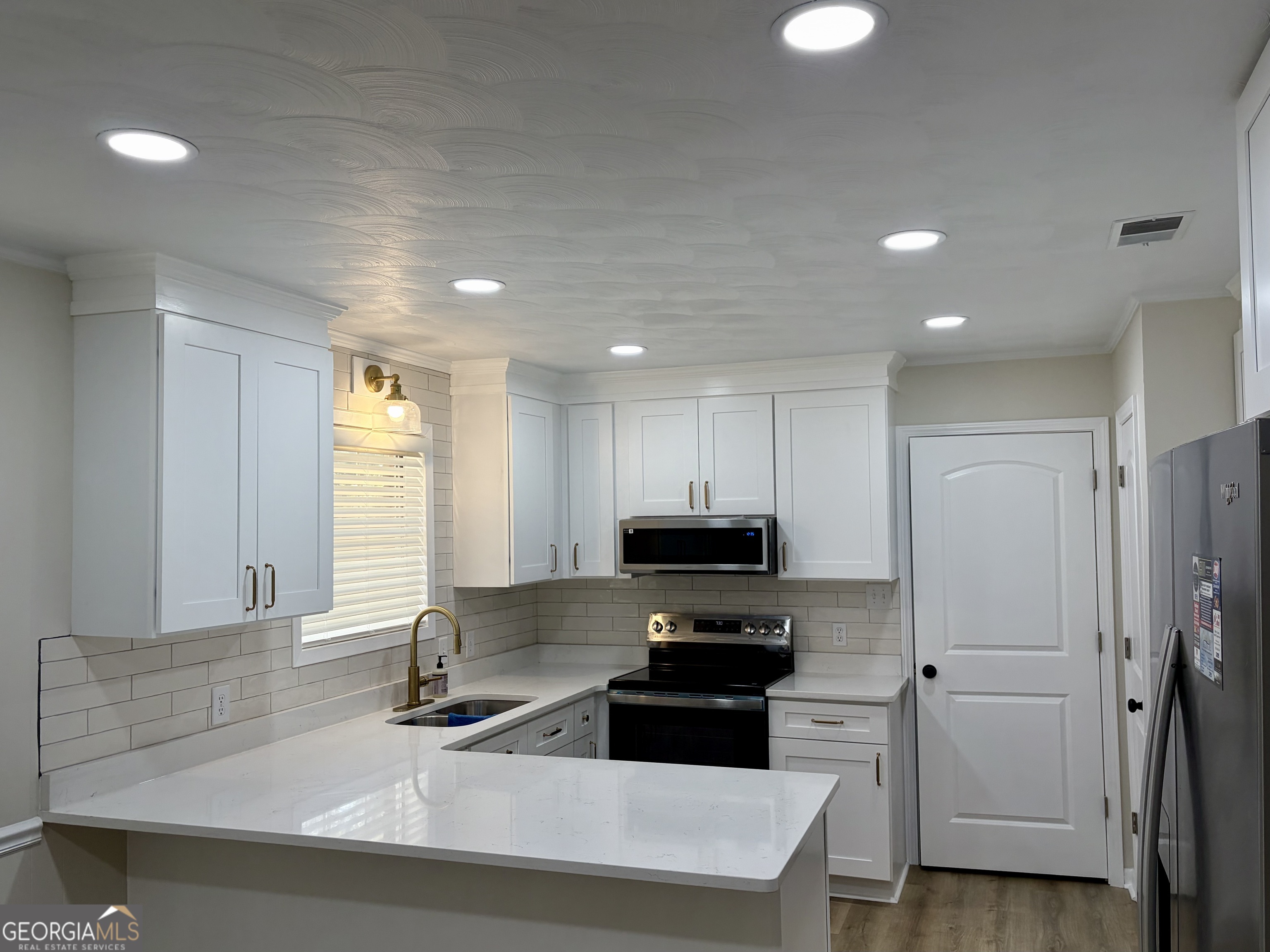72 10th Street McRae-Helena, GA 31037 - Photo 6 of 26 a kitchen with stainless steel appliances a sink a stove a microwave a refrigerator and cabinets