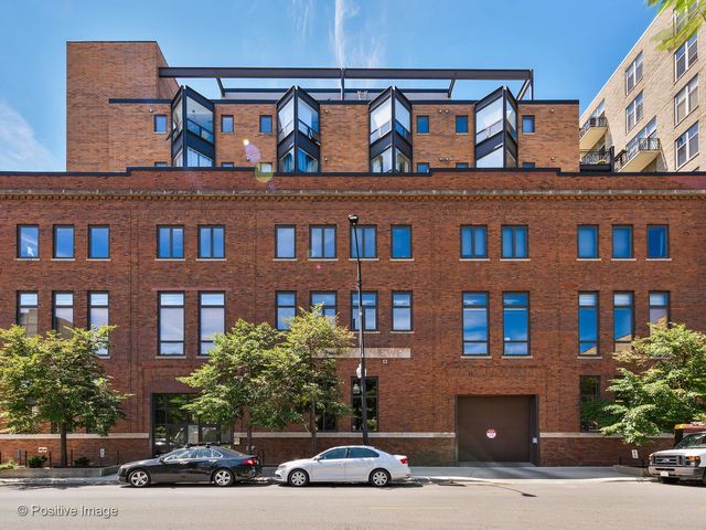 a front view of a building with lot of cars and trees