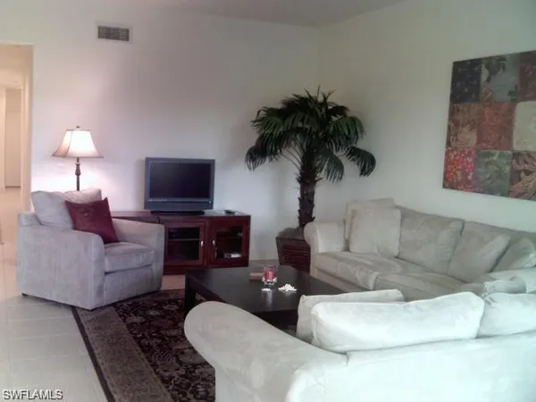 a living room with furniture a lamp and a flat screen tv