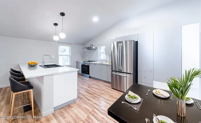 a kitchen with sink refrigerator dining table and chairs