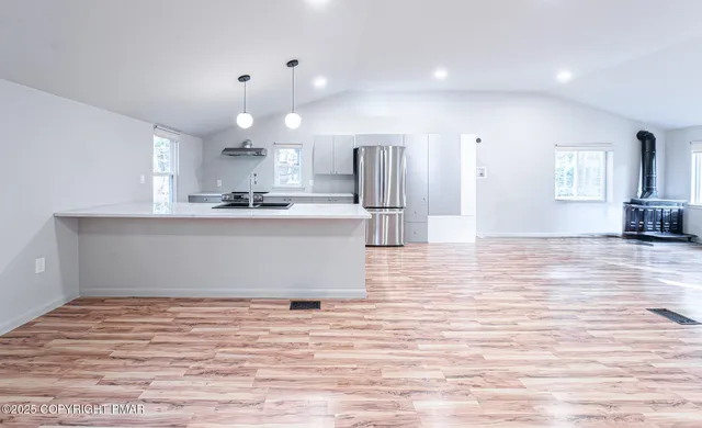 a view of a kitchen with kitchen island a sink wooden floor and a refrigerator