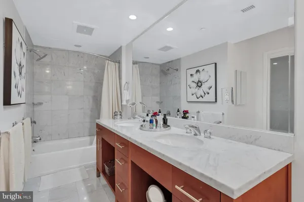a bathroom with a sink double vanity granite tub shower and a mirror