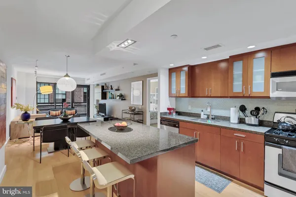 a kitchen with a sink a stove cabinets counter space and living room view