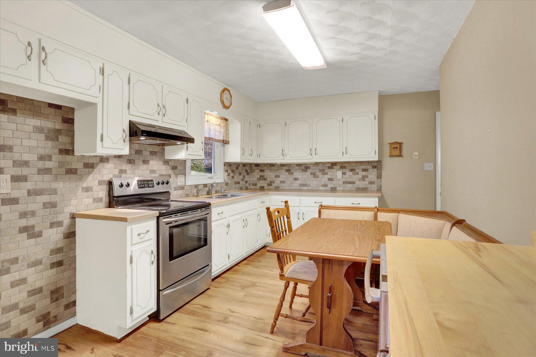 970 Cranes Gap Road Carlisle, PA 17013 - Photo 13 of 48 a kitchen with stainless steel appliances granite countertop a stove a sink dishwasher and white cabinets with wooden floor