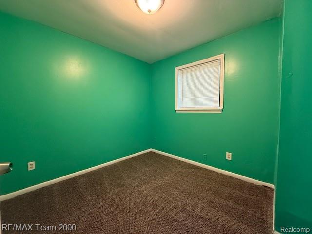 26174 Kitch Street Inkster, MI 48141 - Photo 7 of 8 Interior room featuring green walls, brown carpet, a single window with blinds, white trim, and a ceiling-mounted light fixture