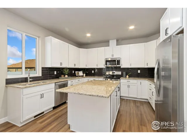 a kitchen with granite countertop white cabinets and white appliances