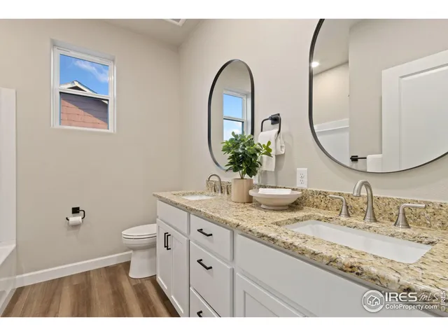 a bathroom with a granite countertop toilet a sink and a mirror