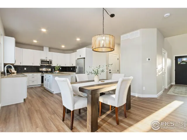 a kitchen with stainless steel appliances kitchen island granite countertop a dining table chairs and a white refrigerator