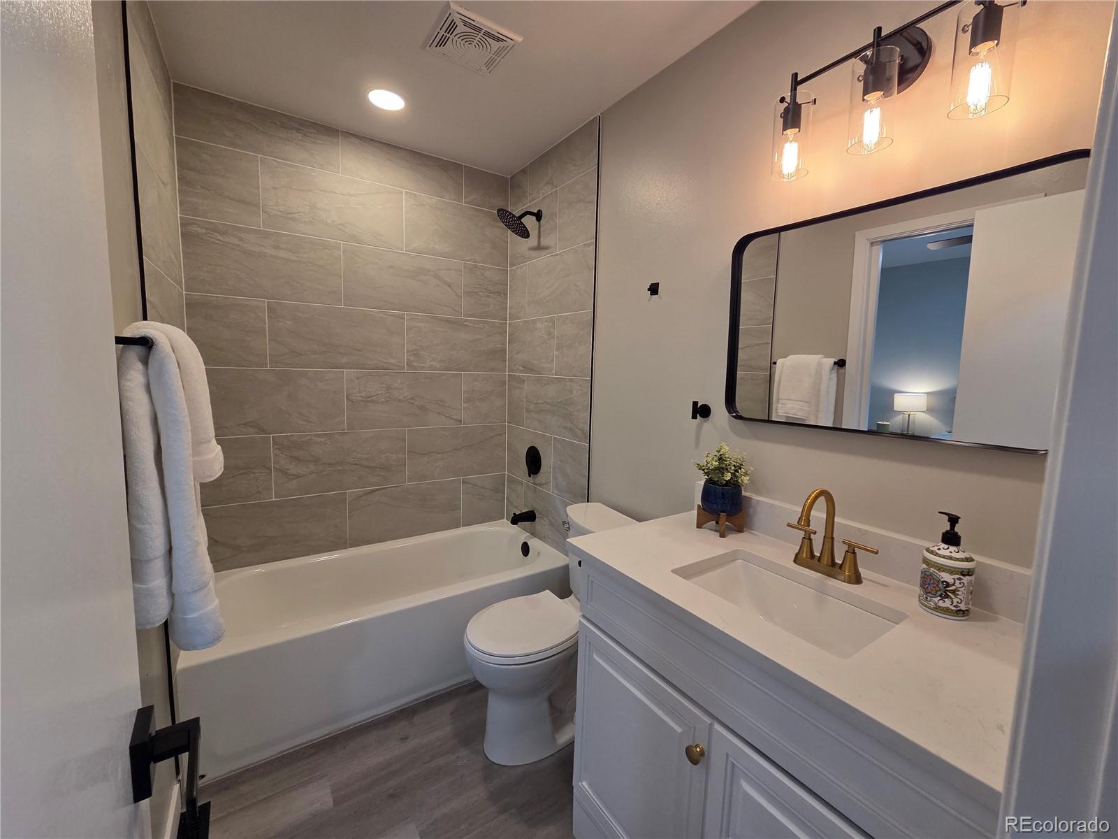 1250 South Monaco Parkway, Unit 17 Denver, CO 80224 - Photo 15 of 29 a bathroom with a bathtub shower sink vanity mirror and toilet