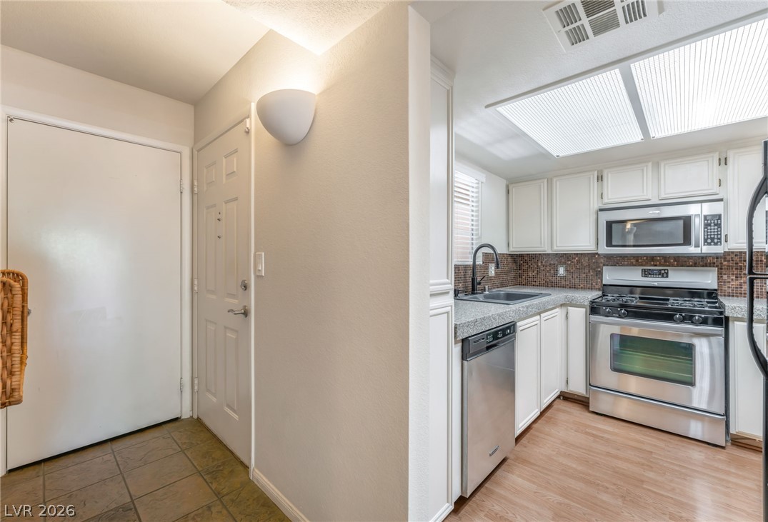 1901 Rio Canyon Court, Unit 102 Las Vegas, NV 89128 - Photo 4 of 23 A compact kitchen with sleek appliances and practical tile flooring awaits culinary endeavors.