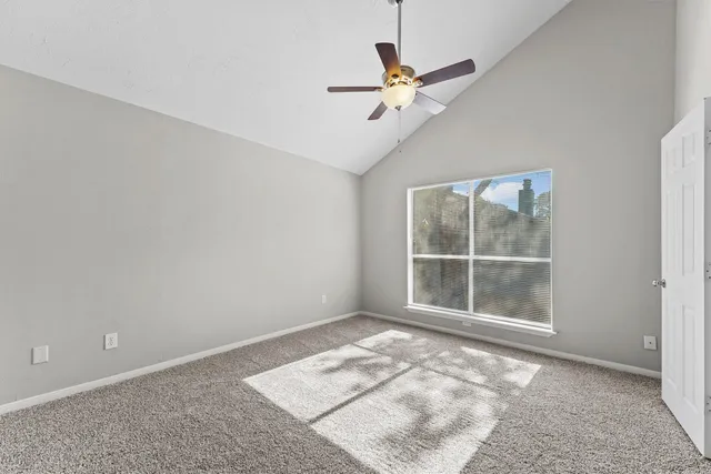 an empty room with ceiling fan and window