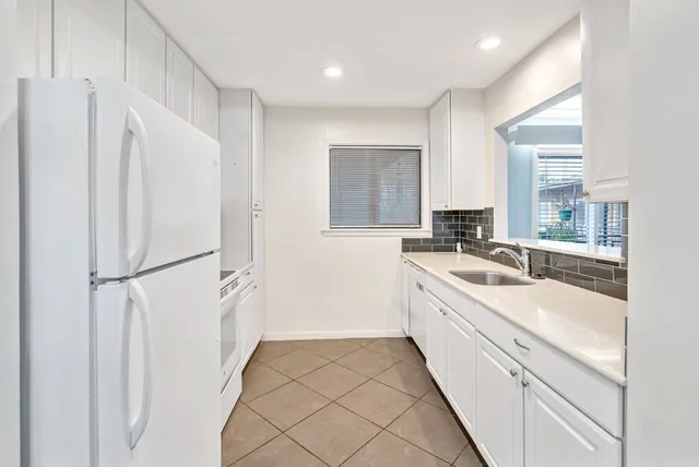 a large white kitchen with a sink and refrigerator