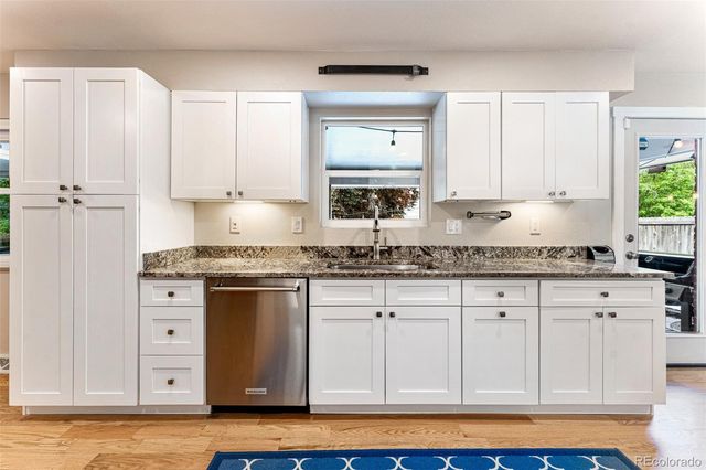a kitchen with granite countertop a sink cabinets and stainless steel appliances