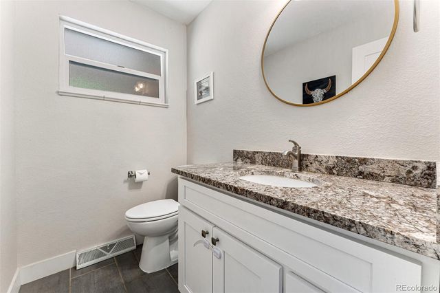 a bathroom with a granite countertop toilet sink and mirror