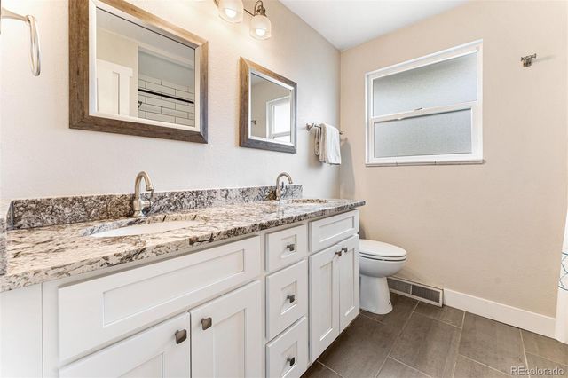a bathroom with a granite countertop toilet sink and mirror