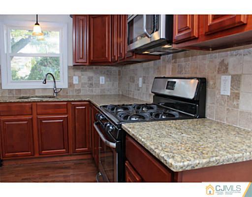 202 Jackson Avenue Edison, NJ 08837 - Photo 6 of 17 a kitchen with stainless steel appliances granite countertop a stove a sink dishwasher and cabinets with wooden floor