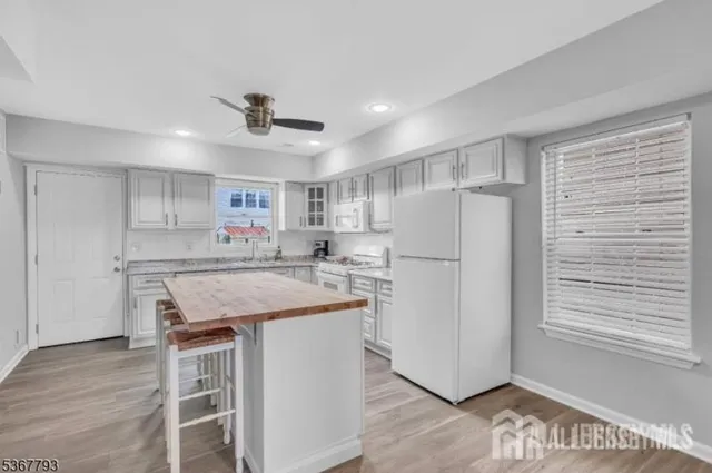 a kitchen with kitchen island a stove a refrigerator cabinets and wooden floor