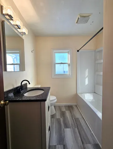 a bathroom with a granite countertop sink a toilet a mirror and vanity