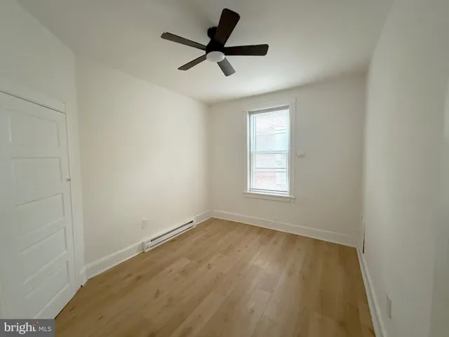 an empty room with a window and a ceiling fan