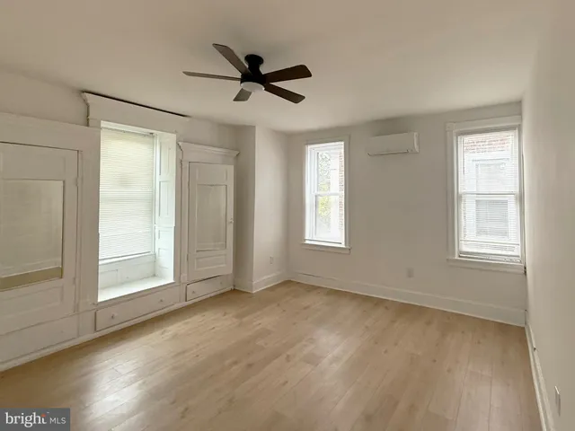 a view of empty room with wooden floor and fan