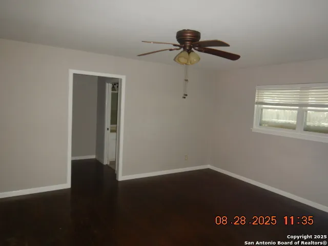 an empty room with wooden floor closet and windows