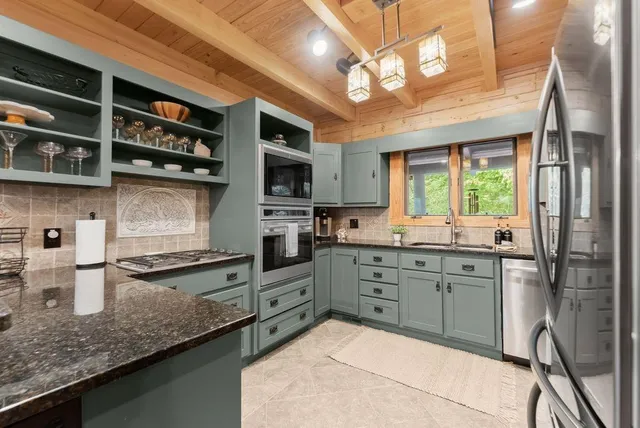 a kitchen with stainless steel appliances kitchen island granite countertop a table chairs and a refrigerator