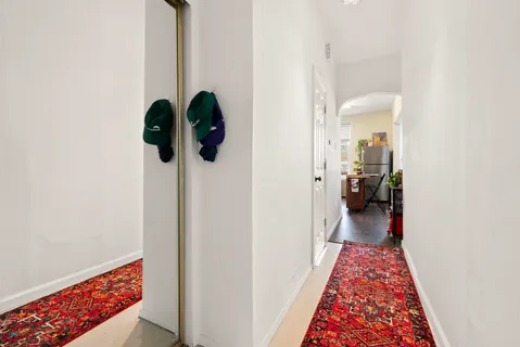 a hallway with a view of bedroom with wooden floor