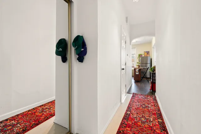 a hallway with a view of bedroom with wooden floor
