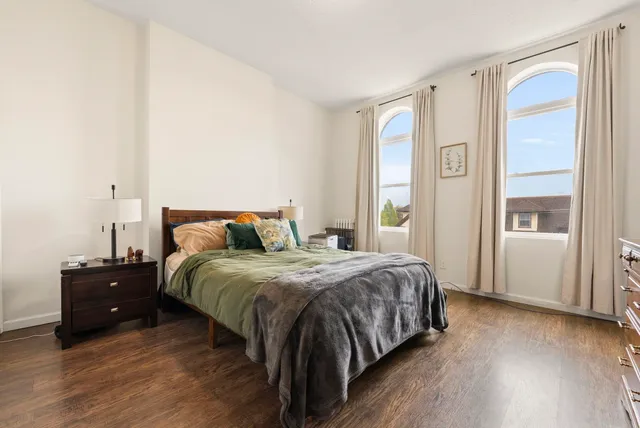 a spacious bedroom with a bed and wooden floor