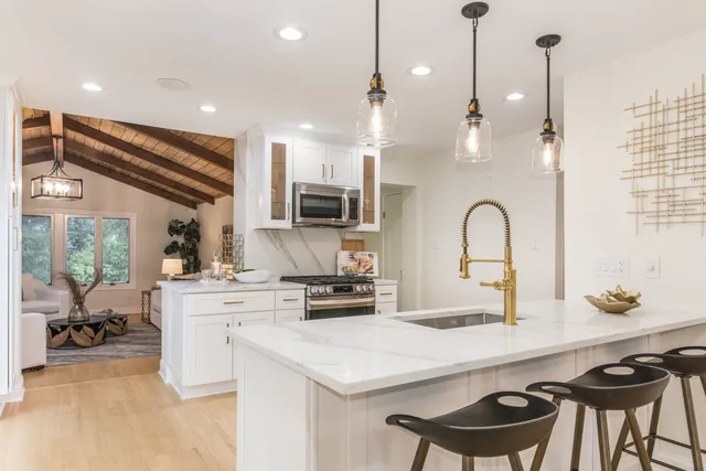 a kitchen with kitchen island a stove a table a sink and cabinets