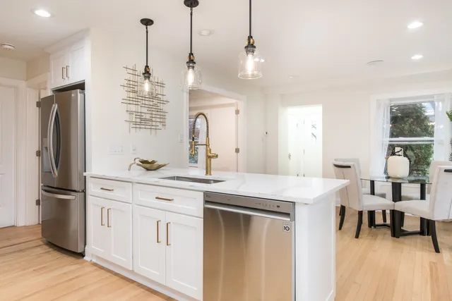a kitchen with kitchen island white cabinets and stainless steel appliances
