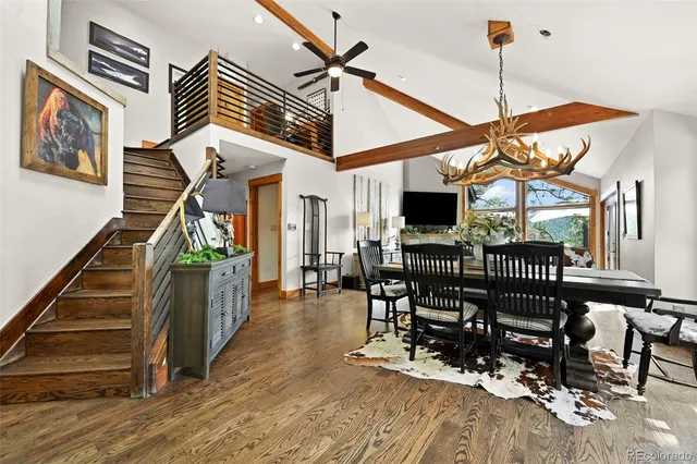 a dining room with wooden floor a chandelier a wooden table and chairs