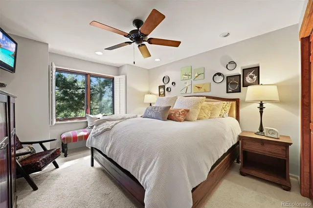a bedroom with a bed a ceiling fan and a window