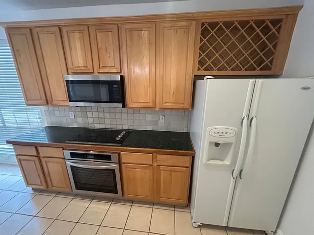 a kitchen with granite countertop a stove top oven microwave and a refrigerator