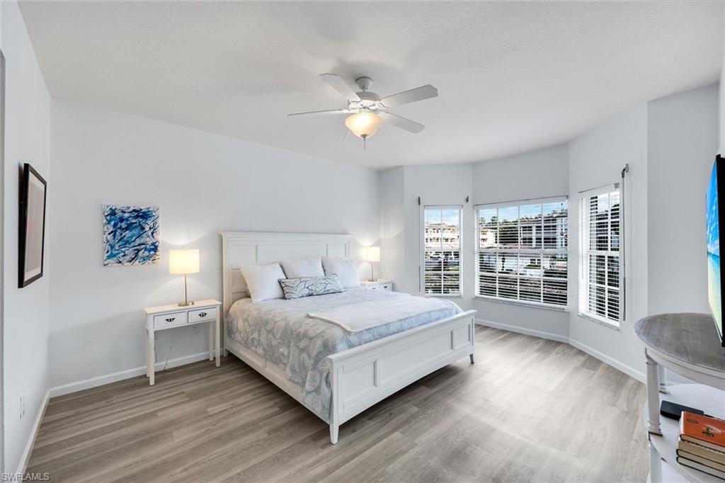 6030 Chardonnay Lane, Unit 203 Naples, FL 34119 - Photo 16 of 28 a bedroom with a large bed and a chandelier