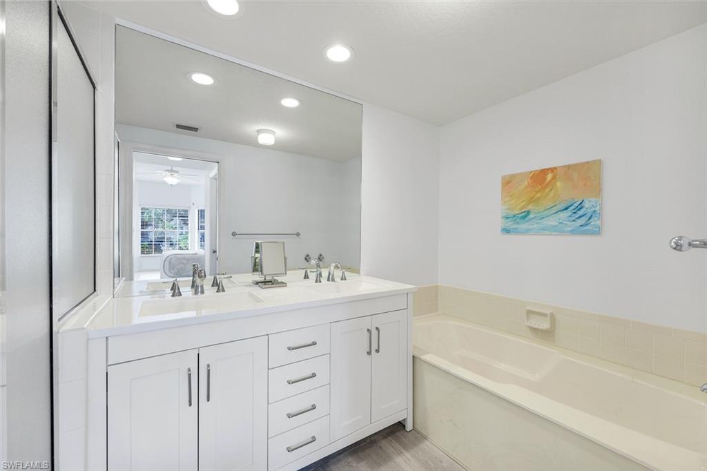 6030 Chardonnay Lane, Unit 203 Naples, FL 34119 - Photo 18 of 28 a bathroom with a double vanity sink tub and a mirror